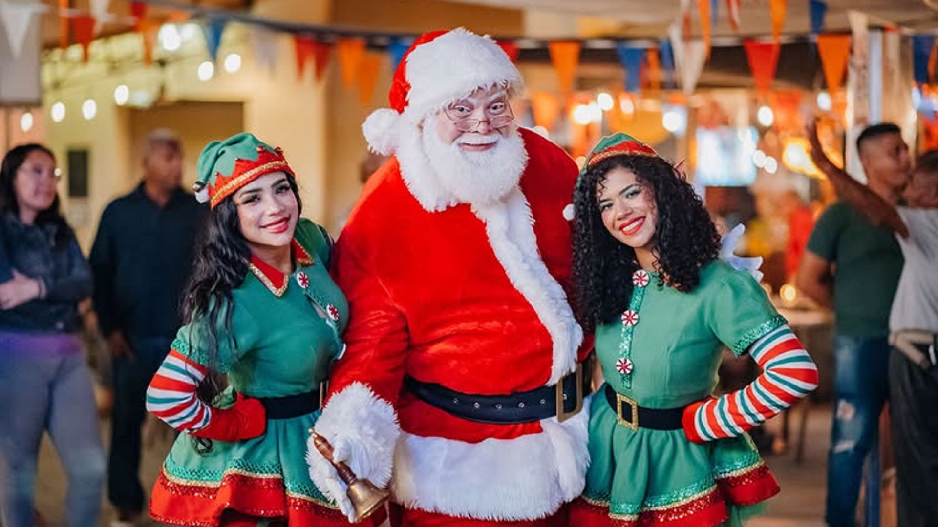 Santa Claus smiling with two elves