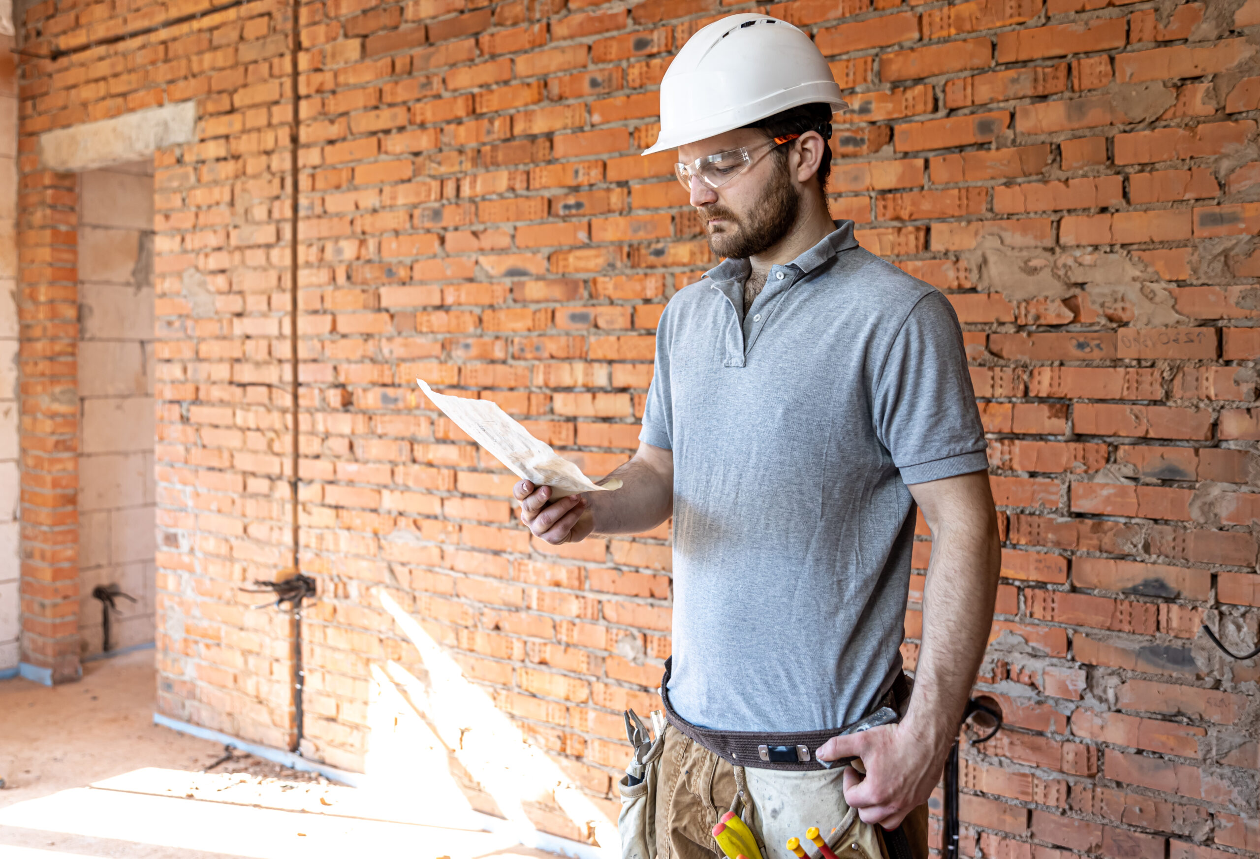 An electrician contractor examines a blueprint at a construction site.