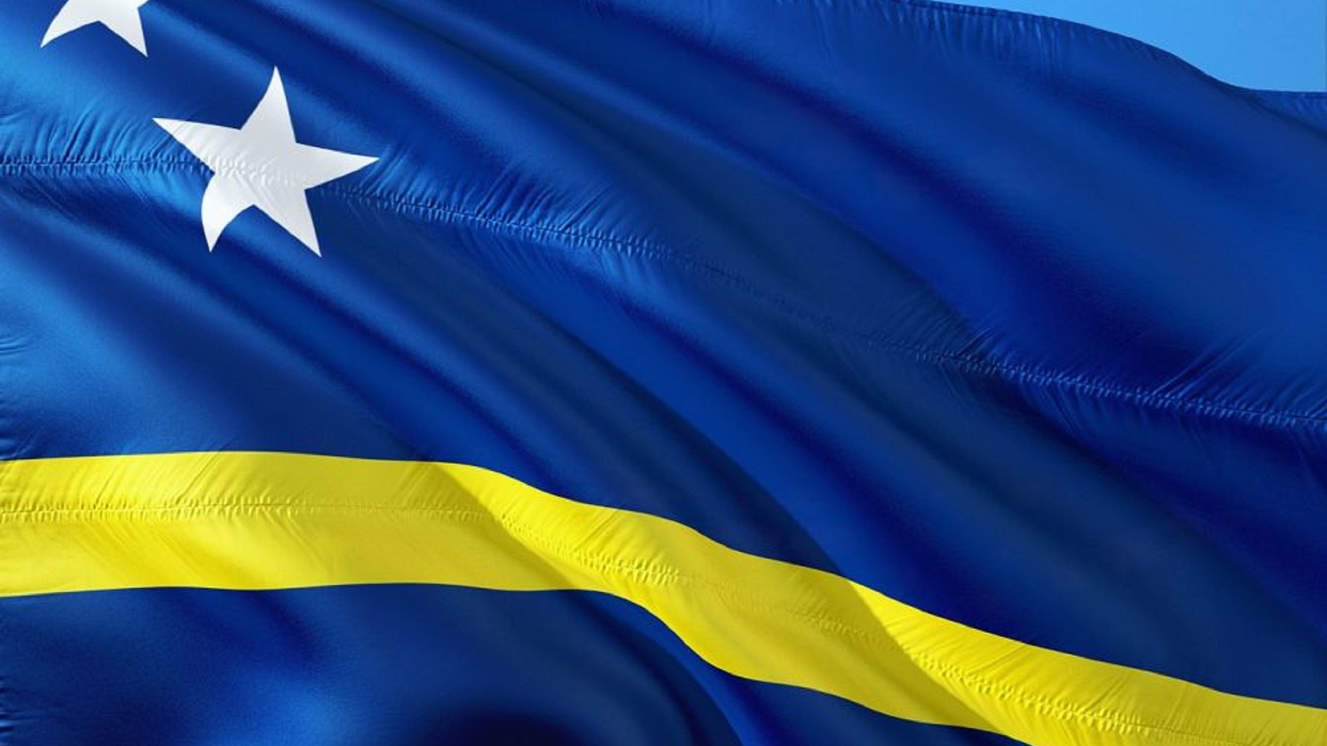 Blue and yellow Curaçao flag with two white stars waving in the wind
