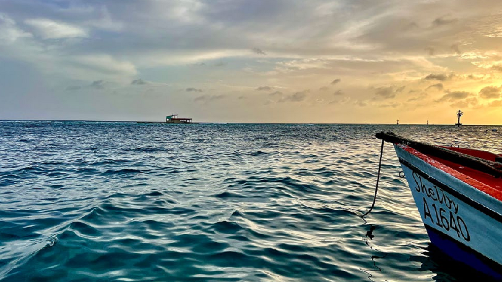 small fishing boat floating on calm ocean waters during a sunset in Aruba
