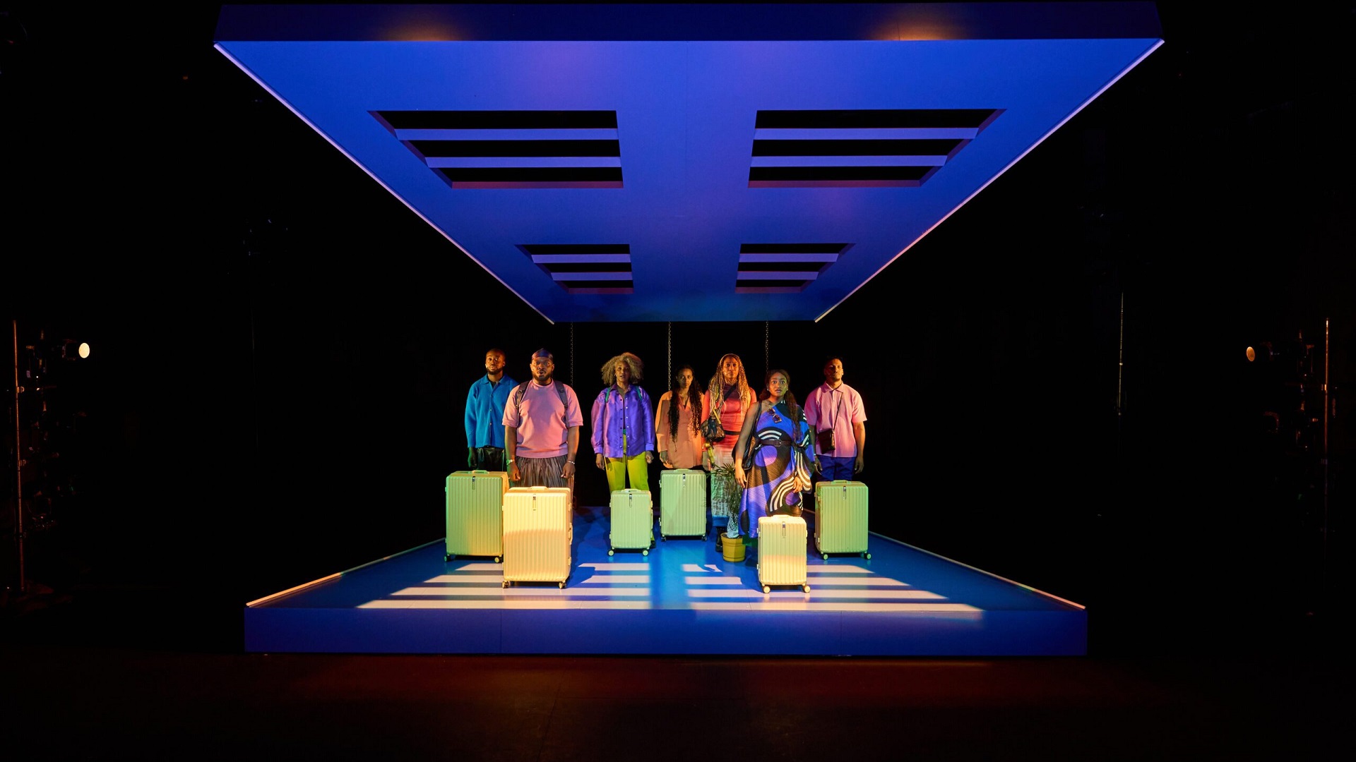 Cast with suitcases symbolizing migration journey in KINGS Come Home Aruba