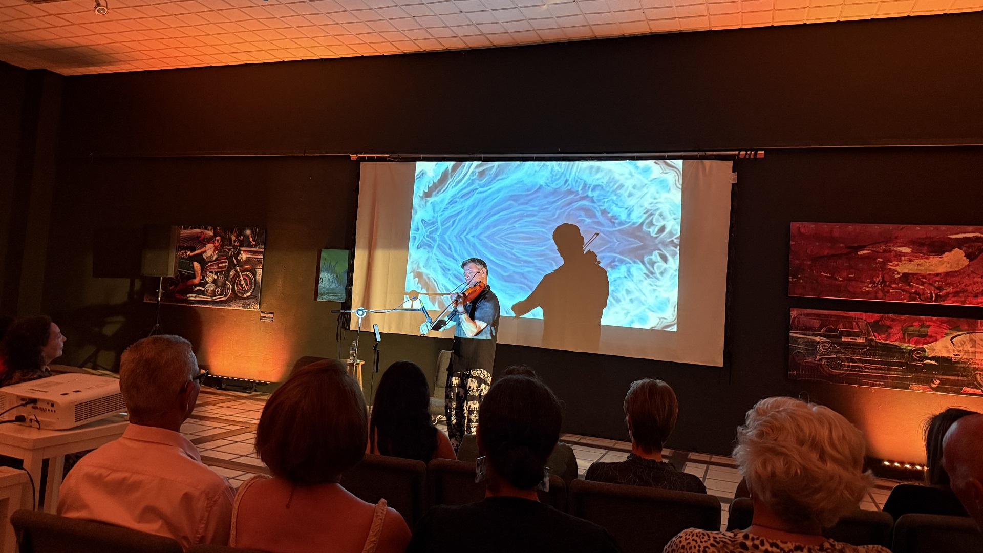 Violinist Vic Renaudéau performing emotional music accompanied by visual art projections in Aruba